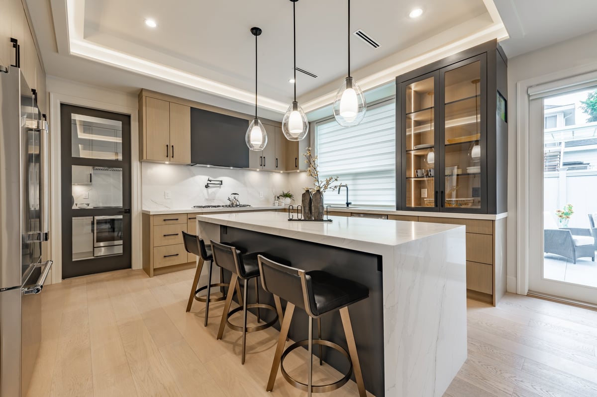 Modern white kitchen with quartz countertops, custom cabinetry, and pendant lighting