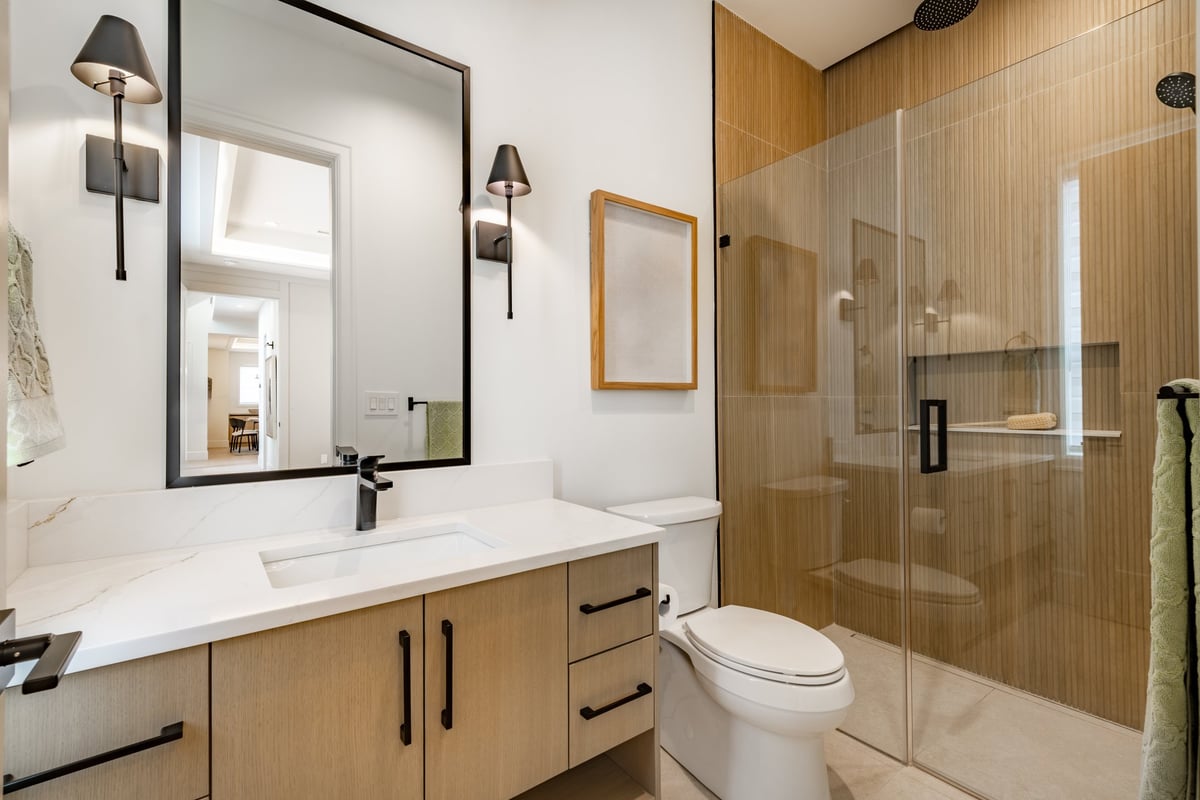 Newly built home bathroom interior primary or master bath with glass wall shower white marble granite floors and countertops