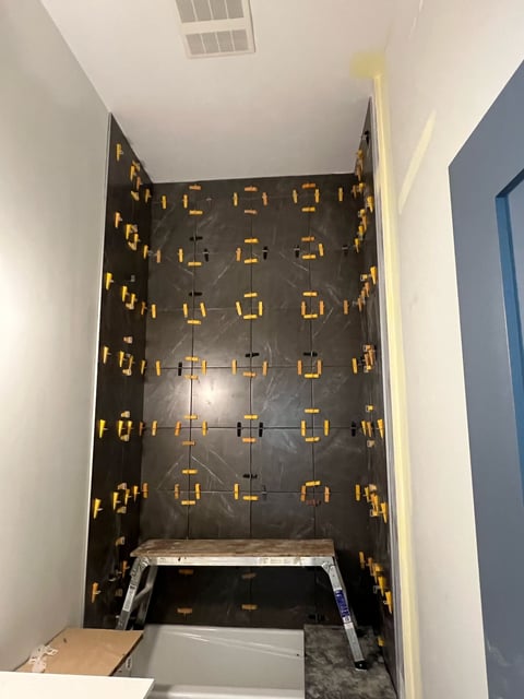 Overhead view of a bathroom shower niche with black marble tile and gold-framed square mirror tiles arranged in rows
