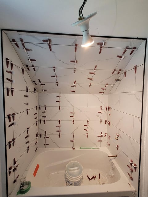 Interior of a bathroom shower with red clothespins clipped to strings covering the walls, ceiling, and fixtures for drying purposes