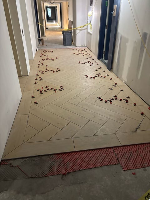 Hallway under construction with herringbone tile flooring pattern and scattered floor debris