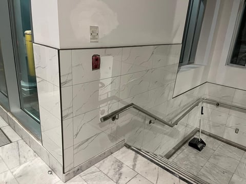 Modern bathroom shower enclosure with marble tile walls and glass panels under construction